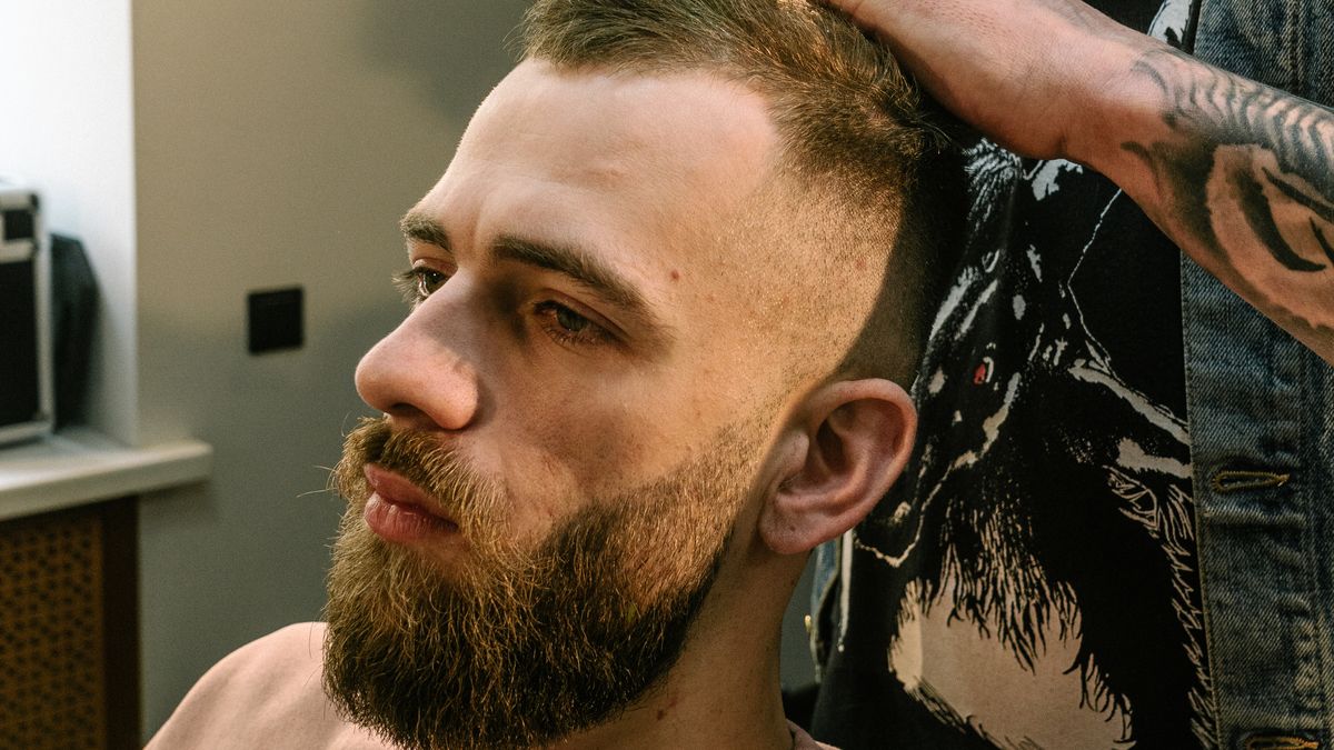 Barber styling a man's hair into a short cut