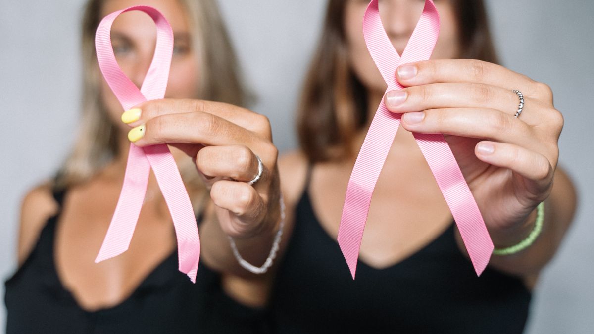 Two women holding pink ribbons in support of breast cancer awareness and early screening