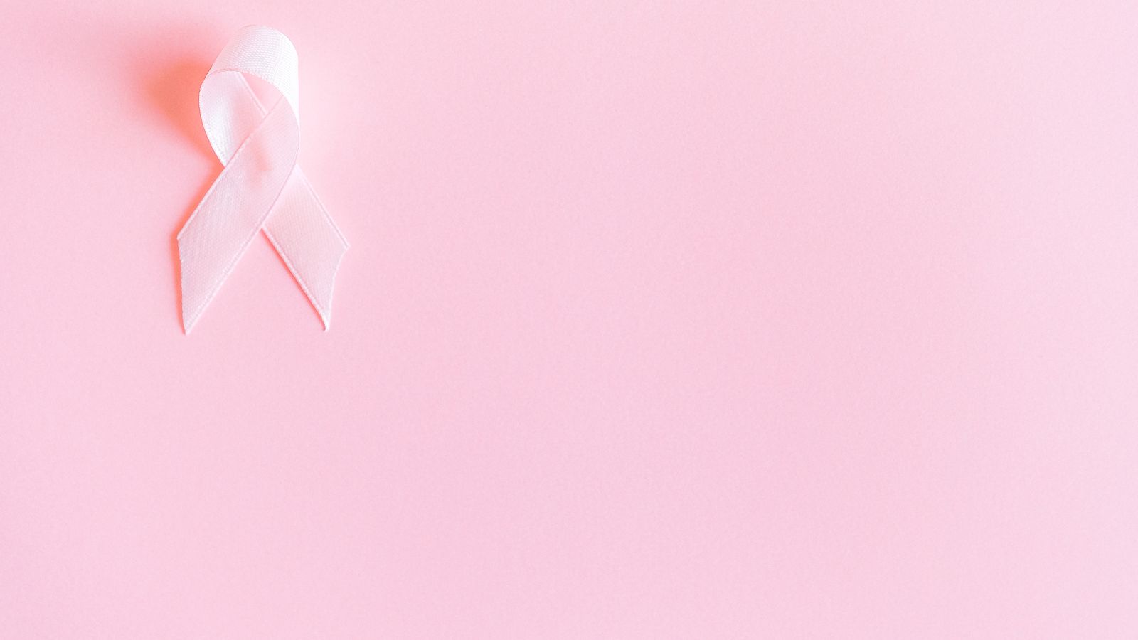 Pink awareness ribbon on a pink background marking Breast Cancer Awareness Month