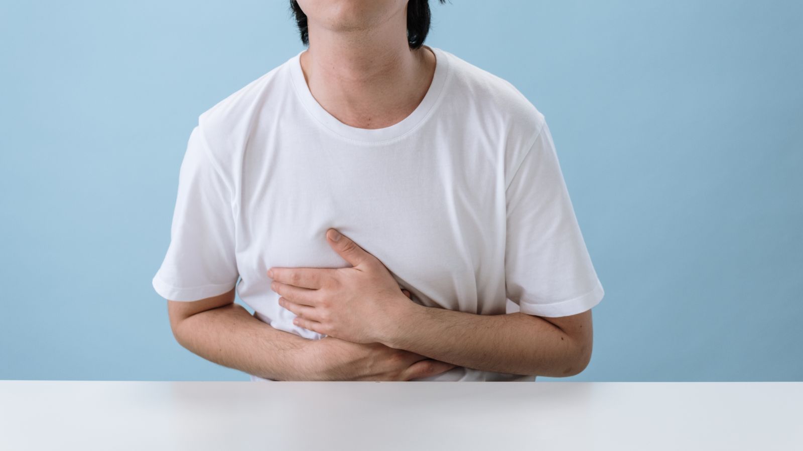 Man holding his upper abdomen after a meal, the typical presentation of gallbladder pain from gallstones