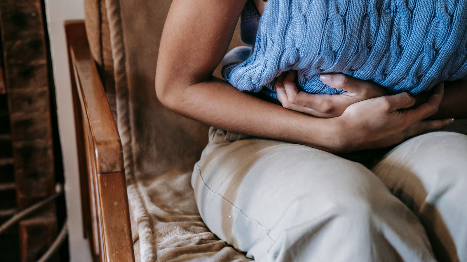 Person holding their side in pain, the flank discomfort common to both kidney stones and kidney infections