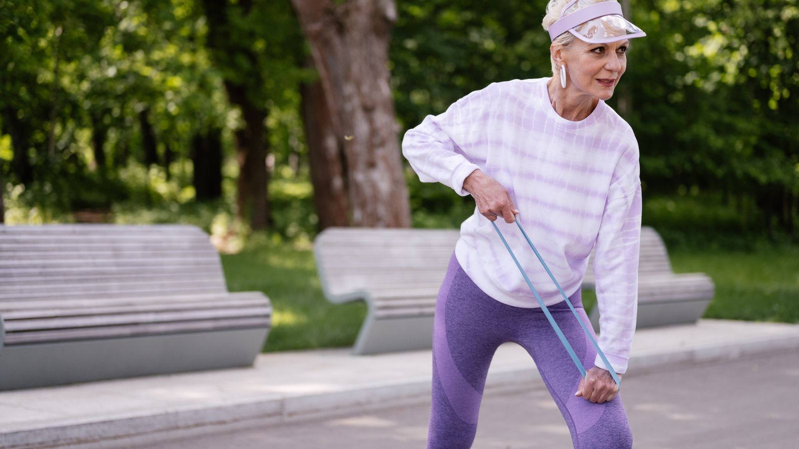 Older woman exercising outdoors with a resistance band, the weight-bearing activity that helps maintain bone density