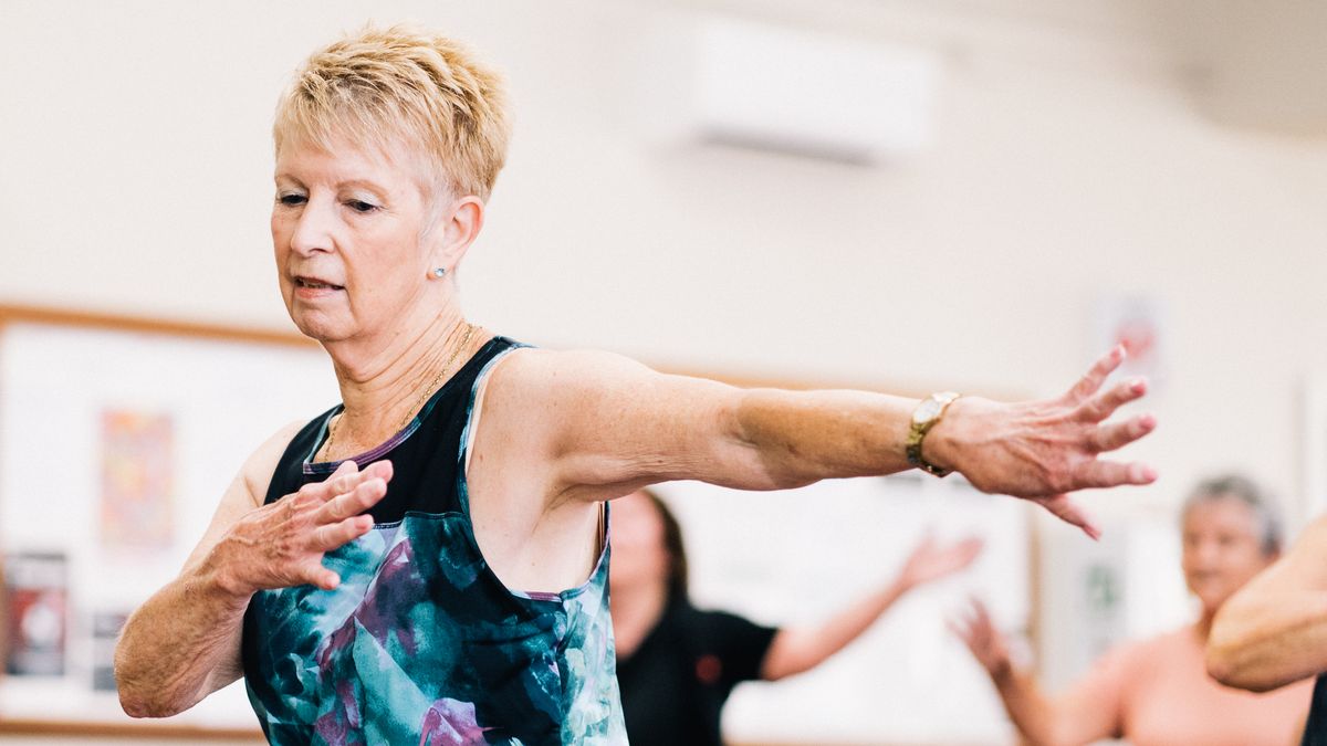 Senior woman taking part in an indoor fitness class, the kind of weight-bearing exercise that supports bone strength
