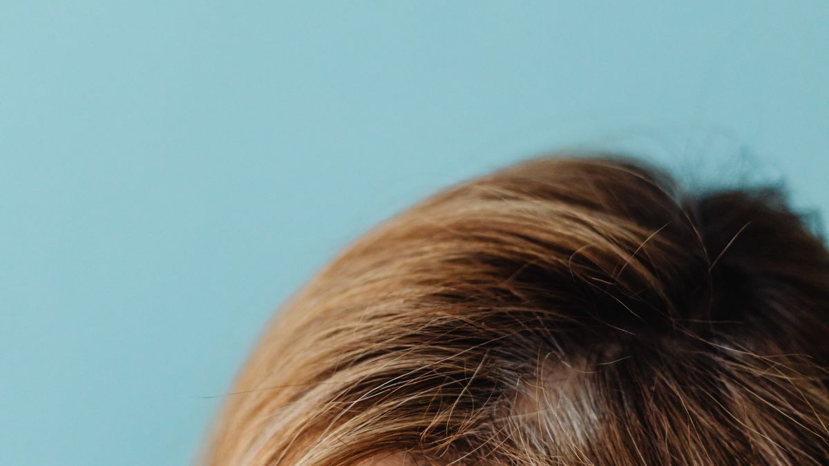 Close-up of a woman's hair parting with more visible scalp, an early sign of hair thinning