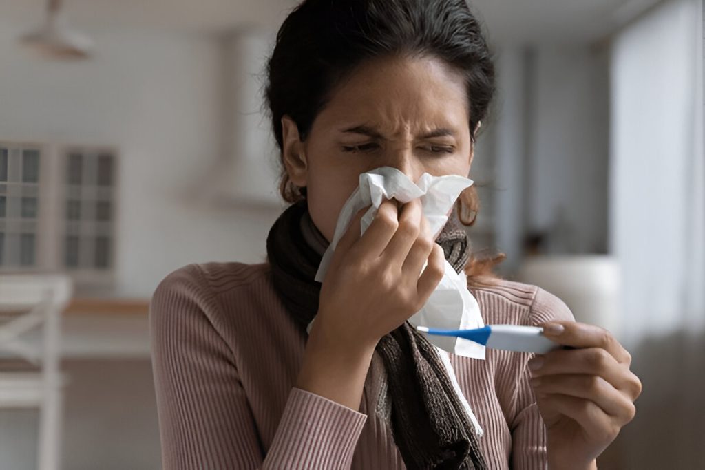 A woman blowing her nose with a tissue, illustrating symptoms of viral fever in Hind